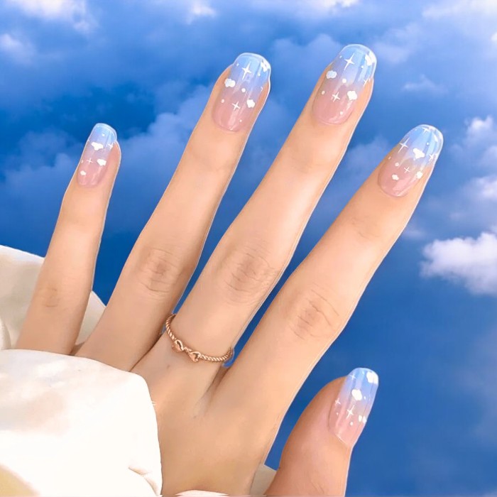 Nails showcasing Cloudy Skies gel wraps, presenting a tranquil light blue manicure adorned with delicate cloud designs.