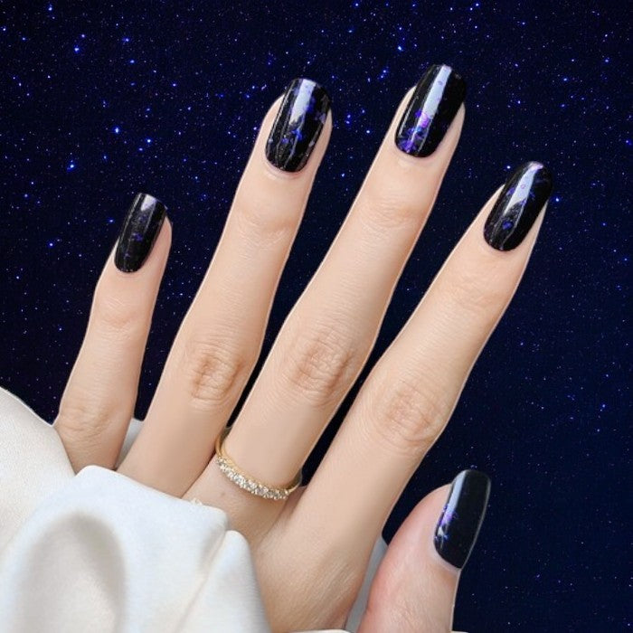 Nails featuring Cosmic gel wraps, showcasing a dark, starry manicure with shimmering specks.