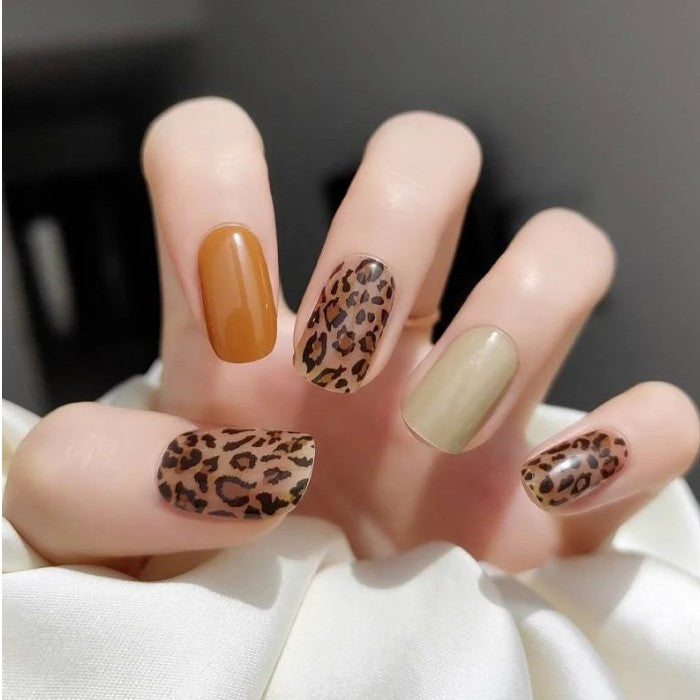 Hands showcasing Wild 'n Free gel nail wraps, presenting a bold leopard print design.